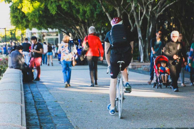 Man Riding Bicycle By People On a pathway. 
